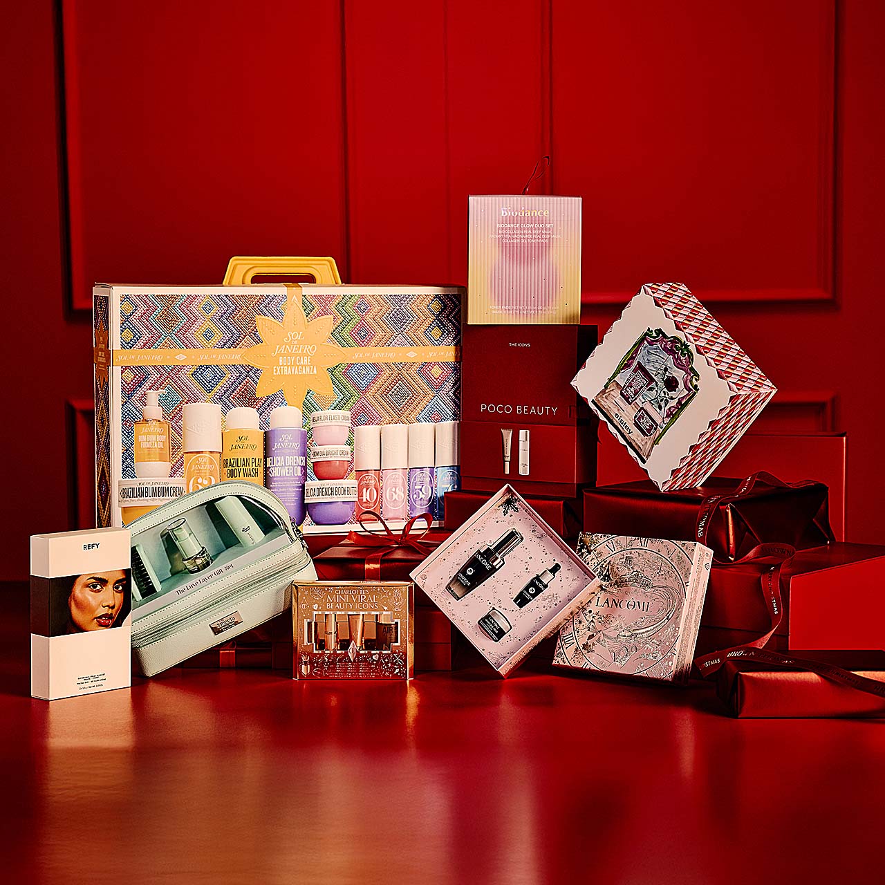 A variety of beauty and skincare products and gift sets arranged against a red background.