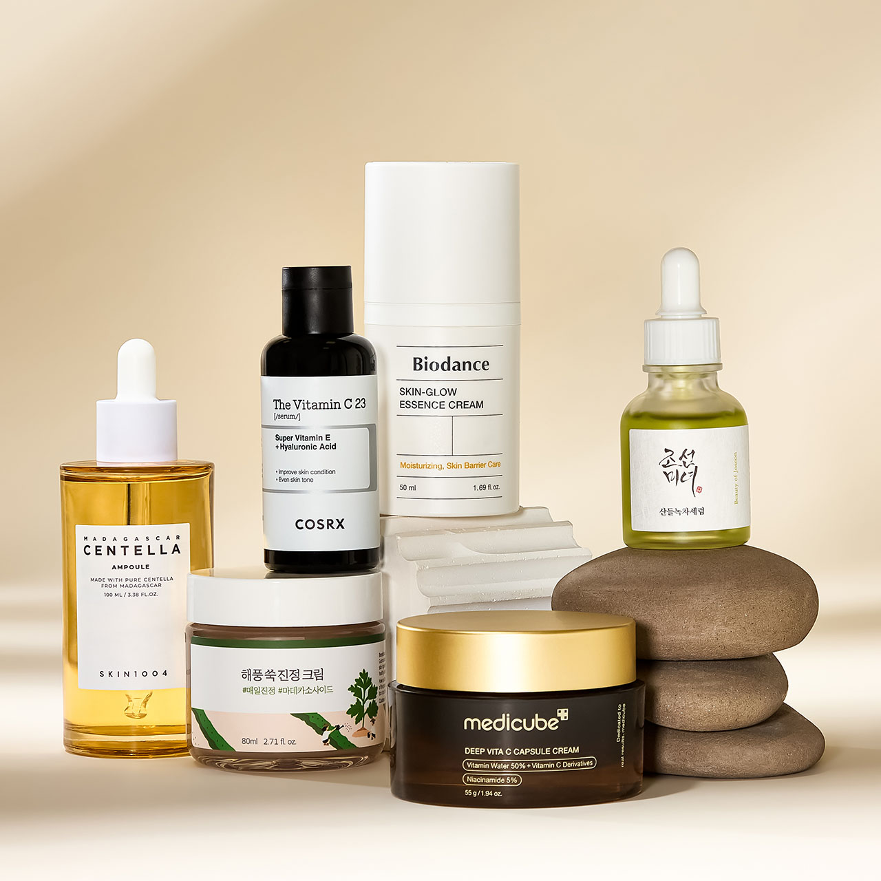 A variety of skincare products, including serums and creams, are displayed on a neutral background alongside smooth stacked stones.