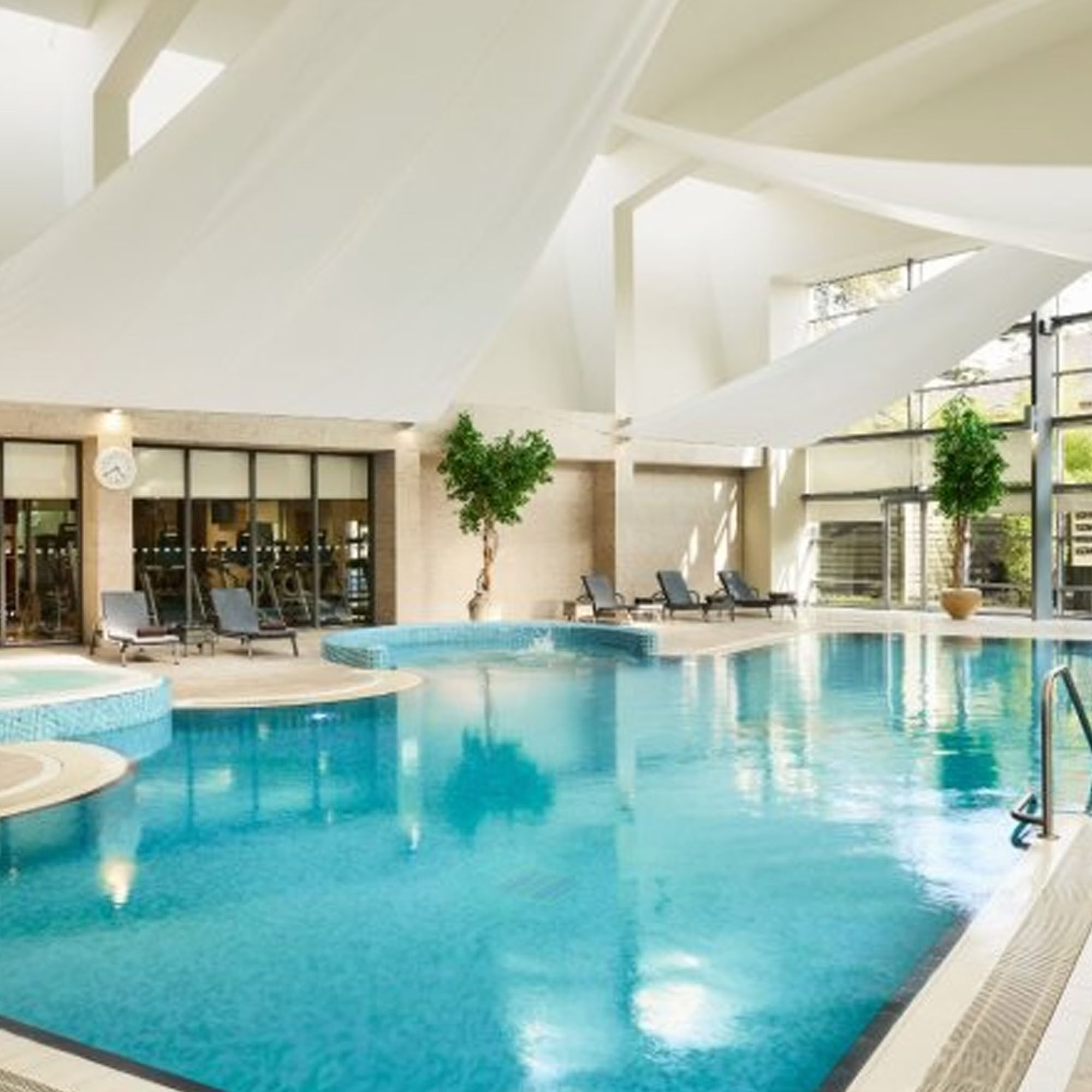 Spacious indoor pool area with loungers, modern architecture, and large windows.