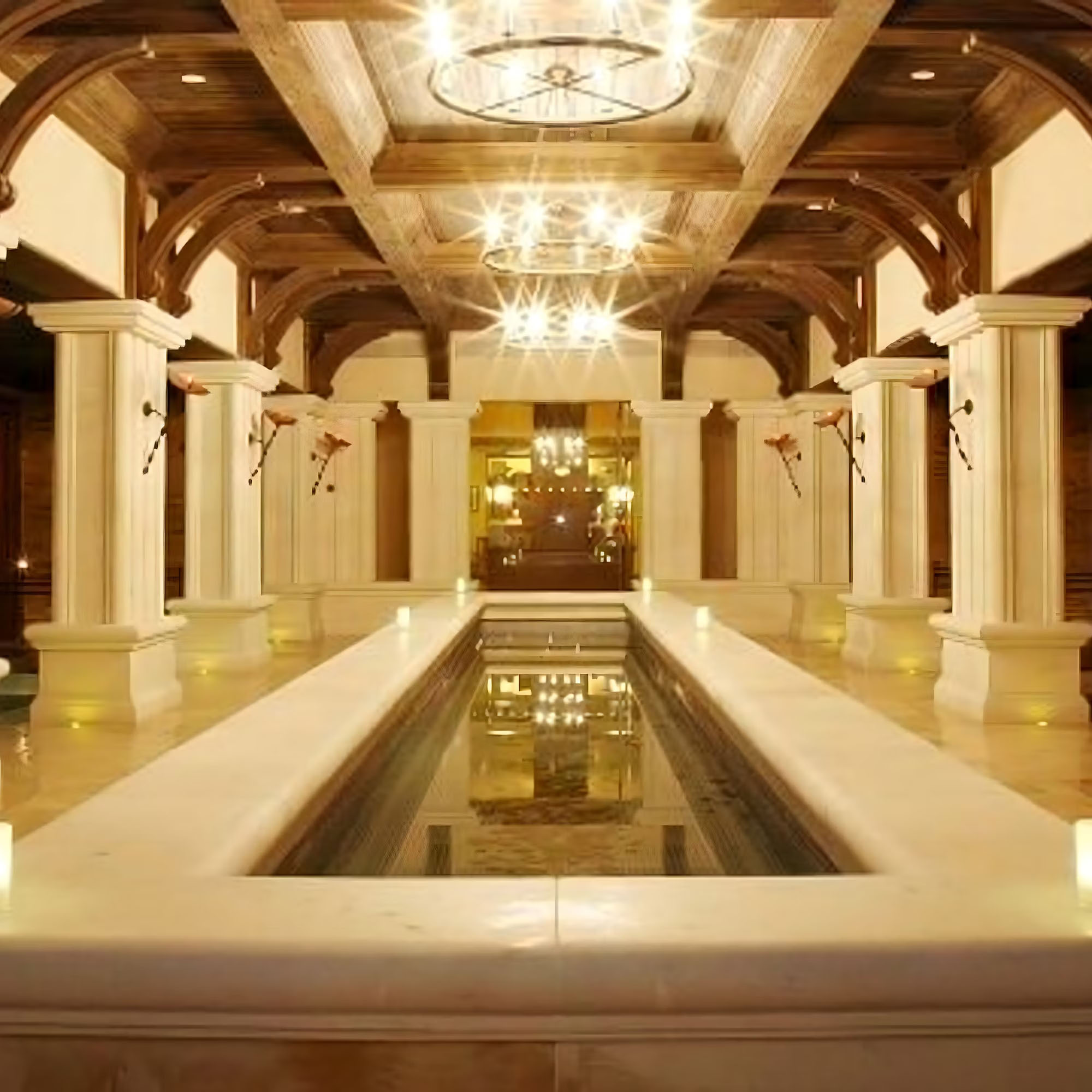 Luxurious interior with a central reflecting pool, ornate chandeliers, wooden beams, and columns.