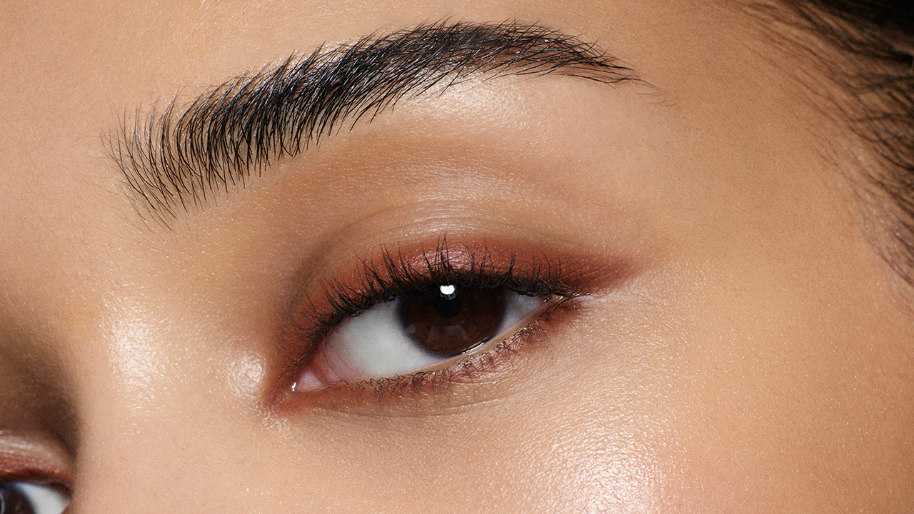 Close-up of a person's eye with defined eyebrows and smooth skin.
