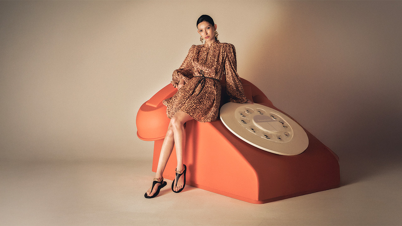 A woman wearing a floral dress sitting on a giant phone