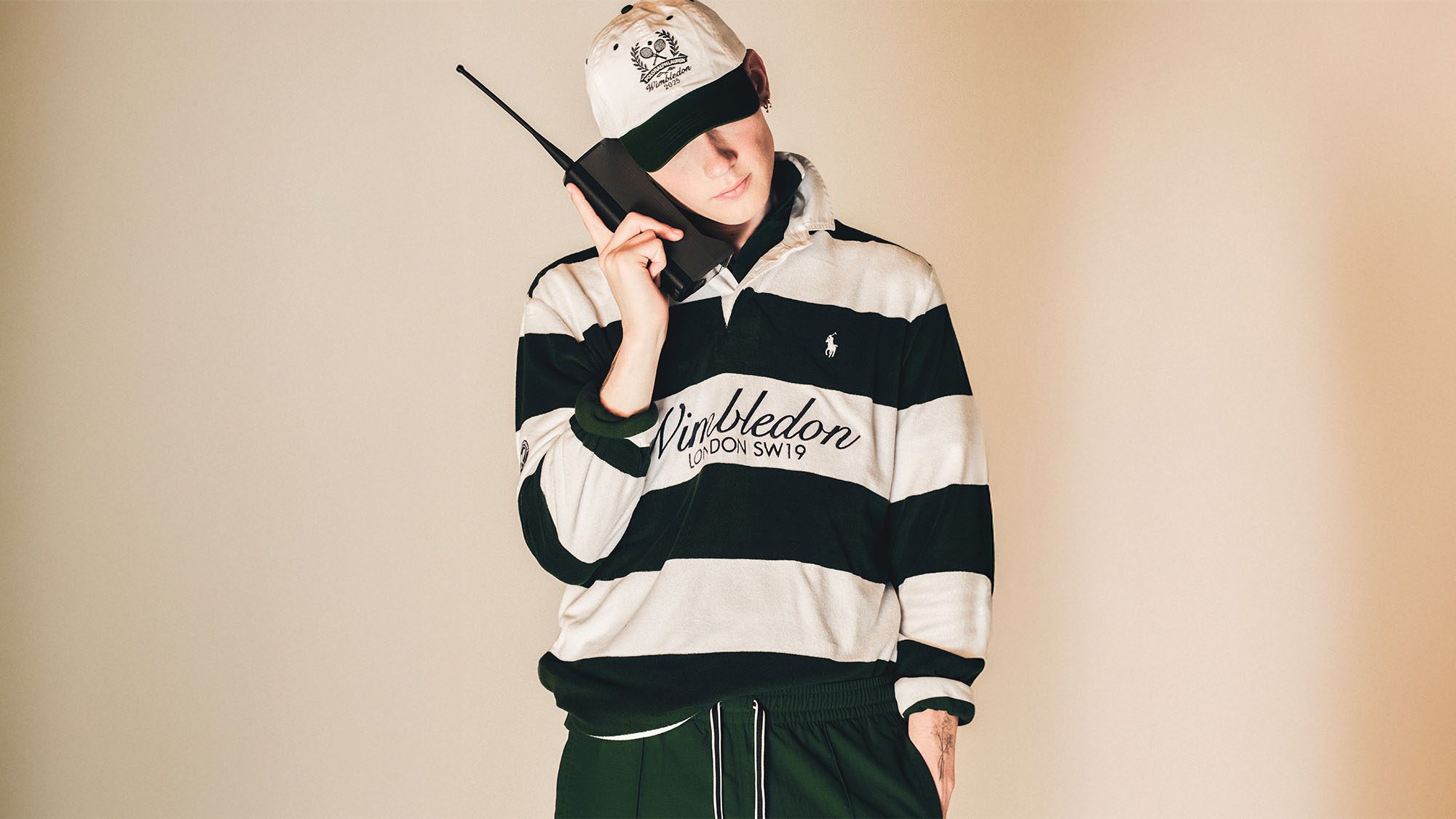 A man looking down holding a phone to his ear wearing the new Ralph Lauren x wimbledon collection 