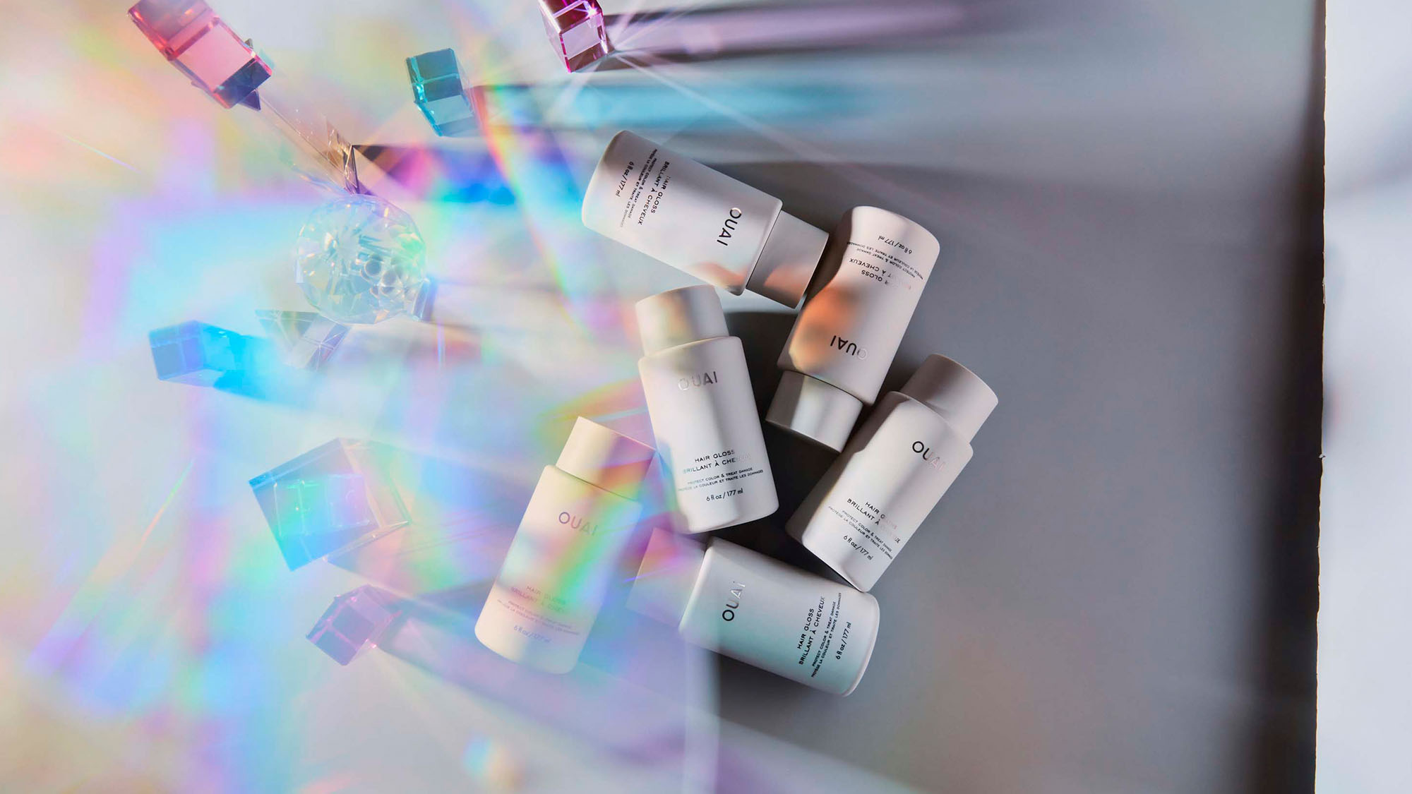 White bottles on a surface with colorful, geometric light reflections.