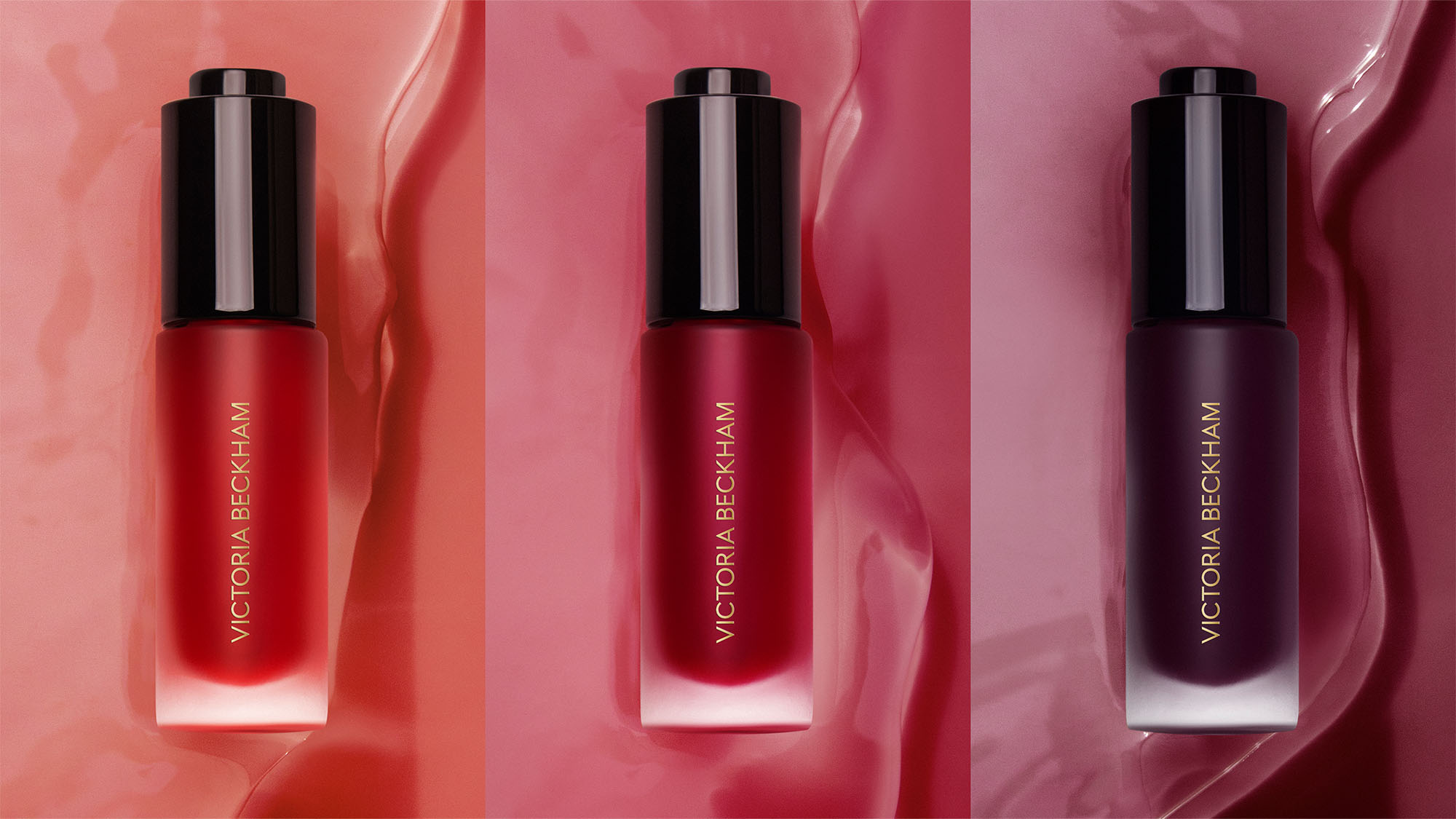 Three Victoria Beckham lipsticks in red, pink, and dark purple shades on a wavy background.