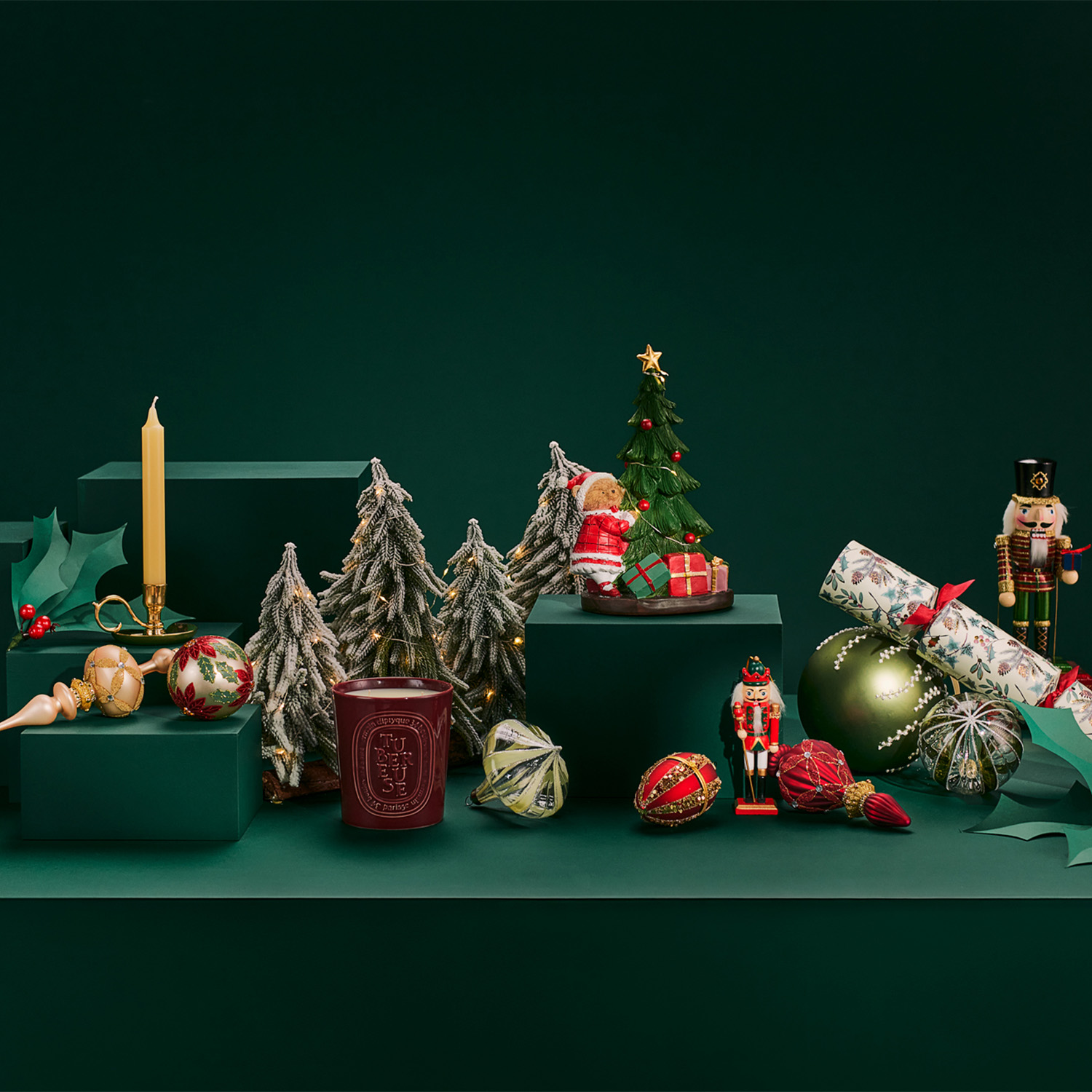 Holiday-themed decor on green platforms includes miniature trees, a candle, ornaments, a nutcracker, and wrapped gifts.