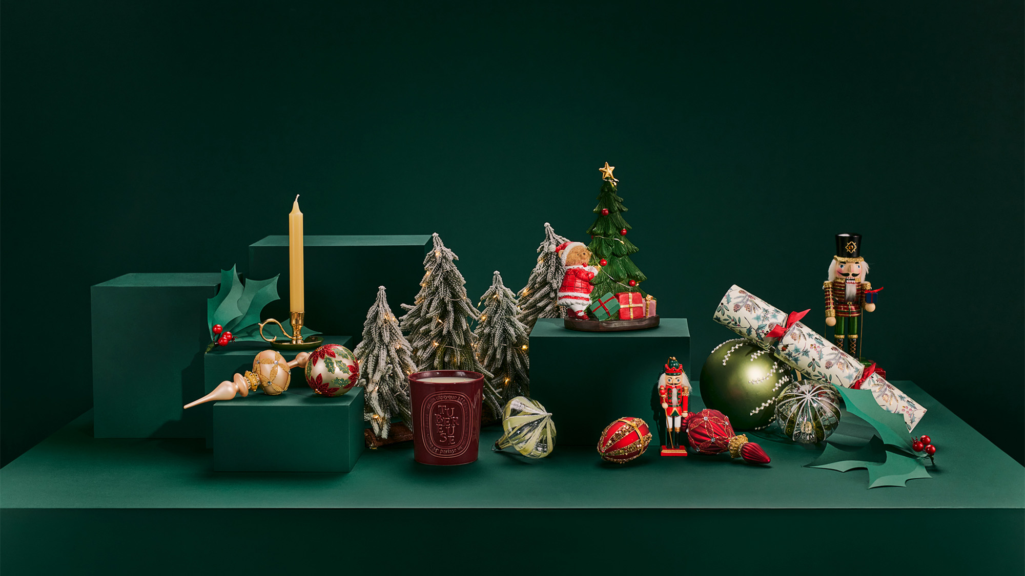 Holiday-themed decor on green platforms includes miniature trees, a candle, ornaments, a nutcracker, and wrapped gifts.