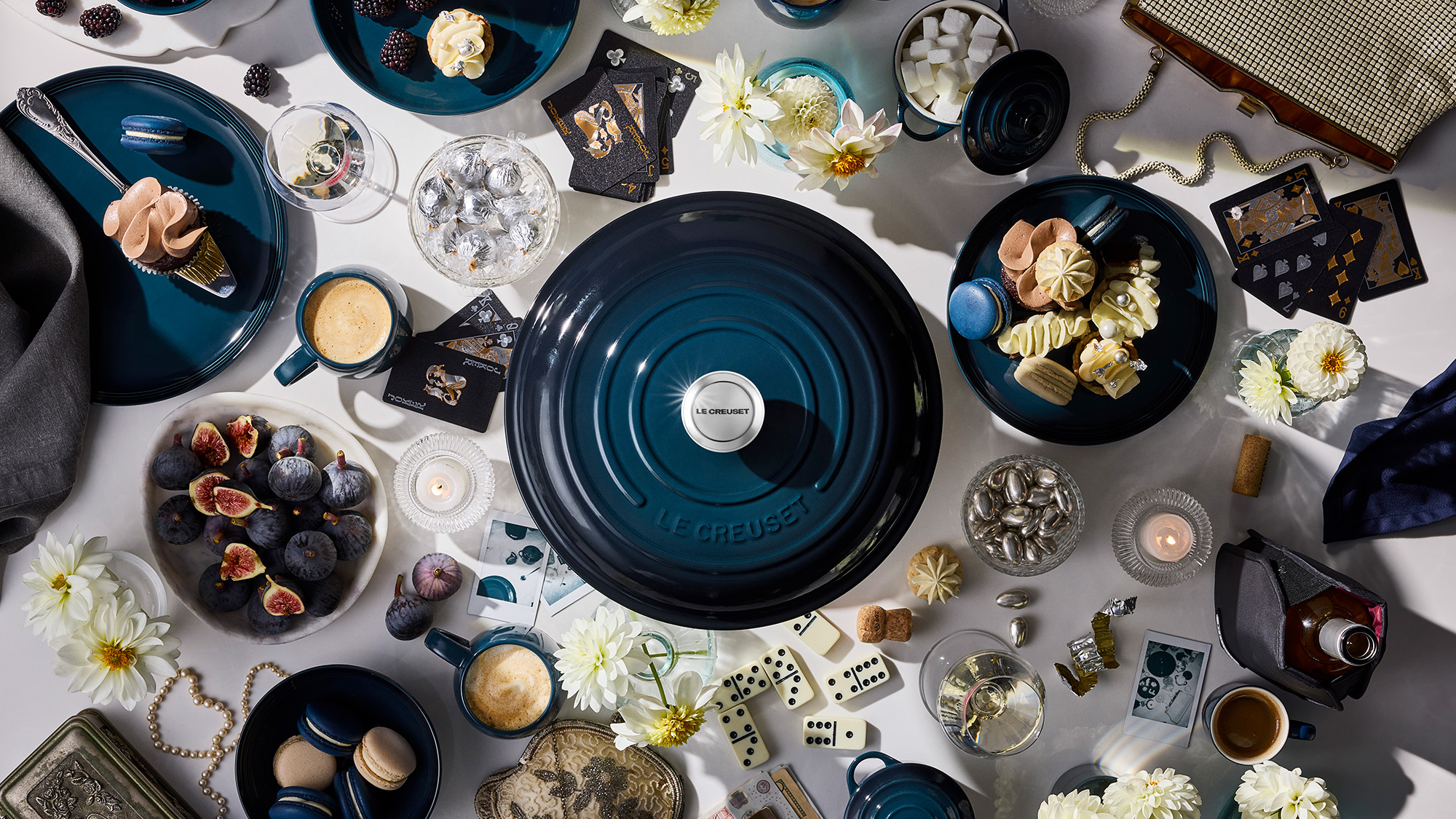 A table with a teal pot, desserts, drinks, flowers, and decorative items arranged aesthetically.