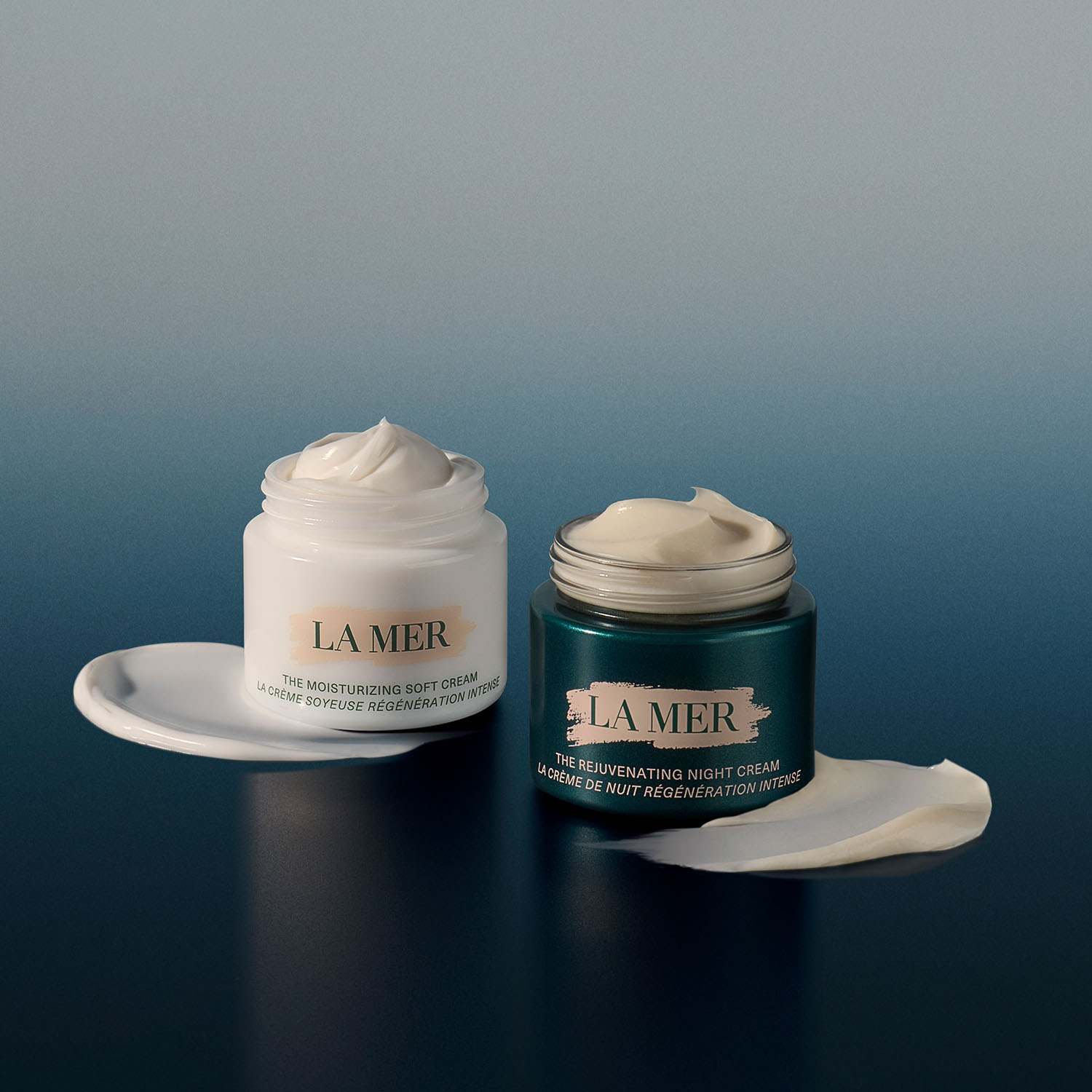 Two jars of La Mer moisturizing creams, one white and one green, with swirled cream on top against a gradient background.