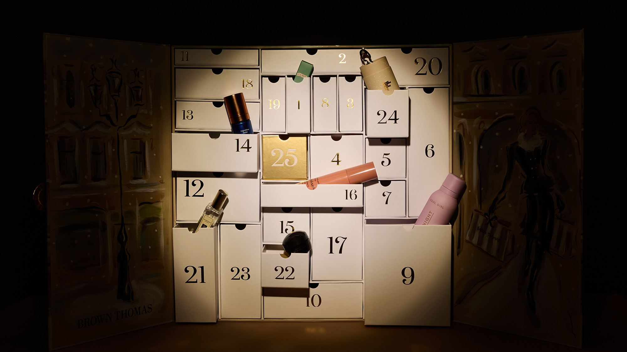 An illuminated advent calendar with open compartments, displaying various small items, set against a dark background.