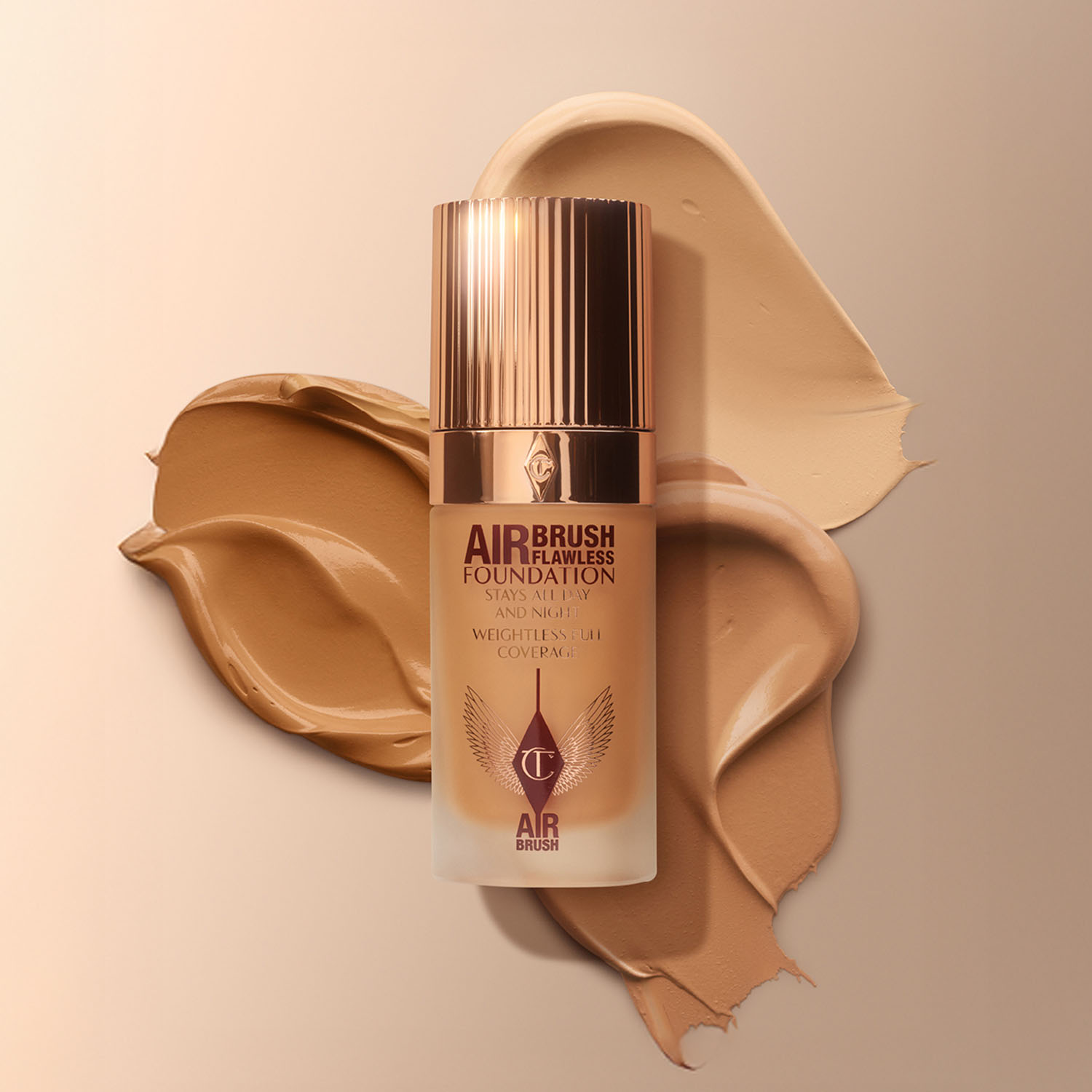 A foundation bottle with bronze cap on beige and brown swatches of makeup.