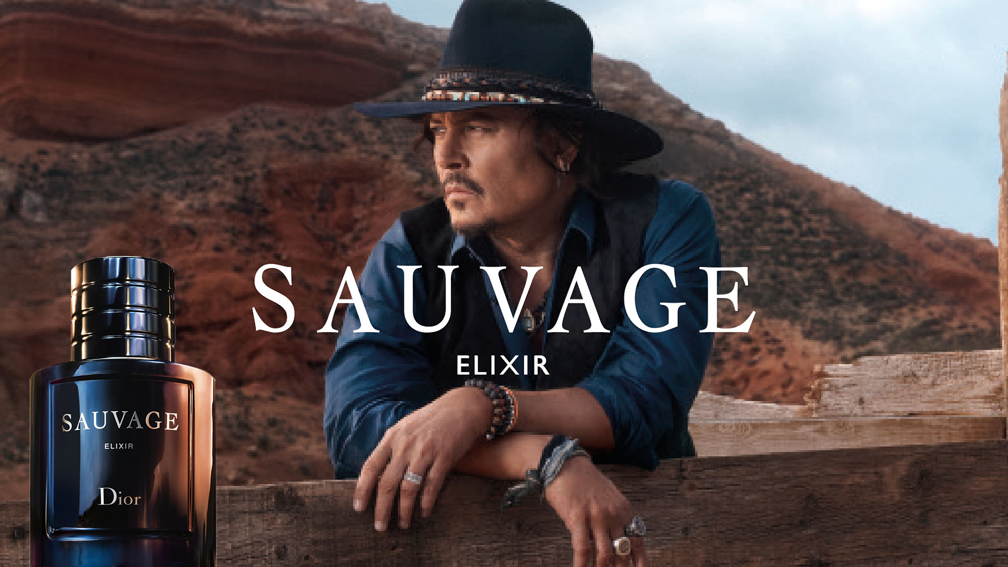 A person in a hat leans on a wooden ledge with 'Sauvage Elixir' and a Dior bottle in the foreground against a rocky landscape.