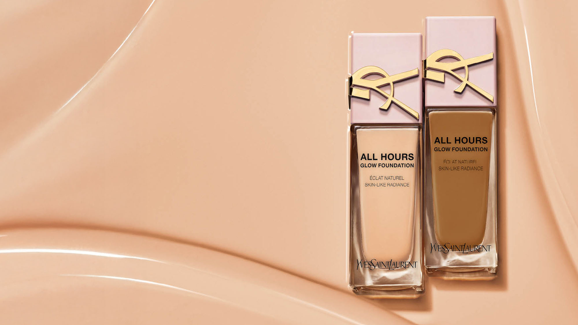 Two bottles of foundation with pink caps and gold detailing on a beige textured background.