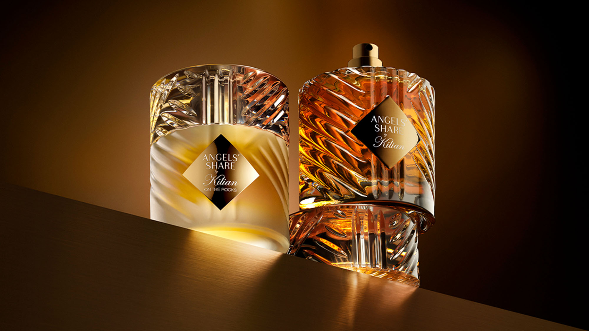 Two elegant perfume bottles with angular designs and labels, set against a dark, warm-toned background.