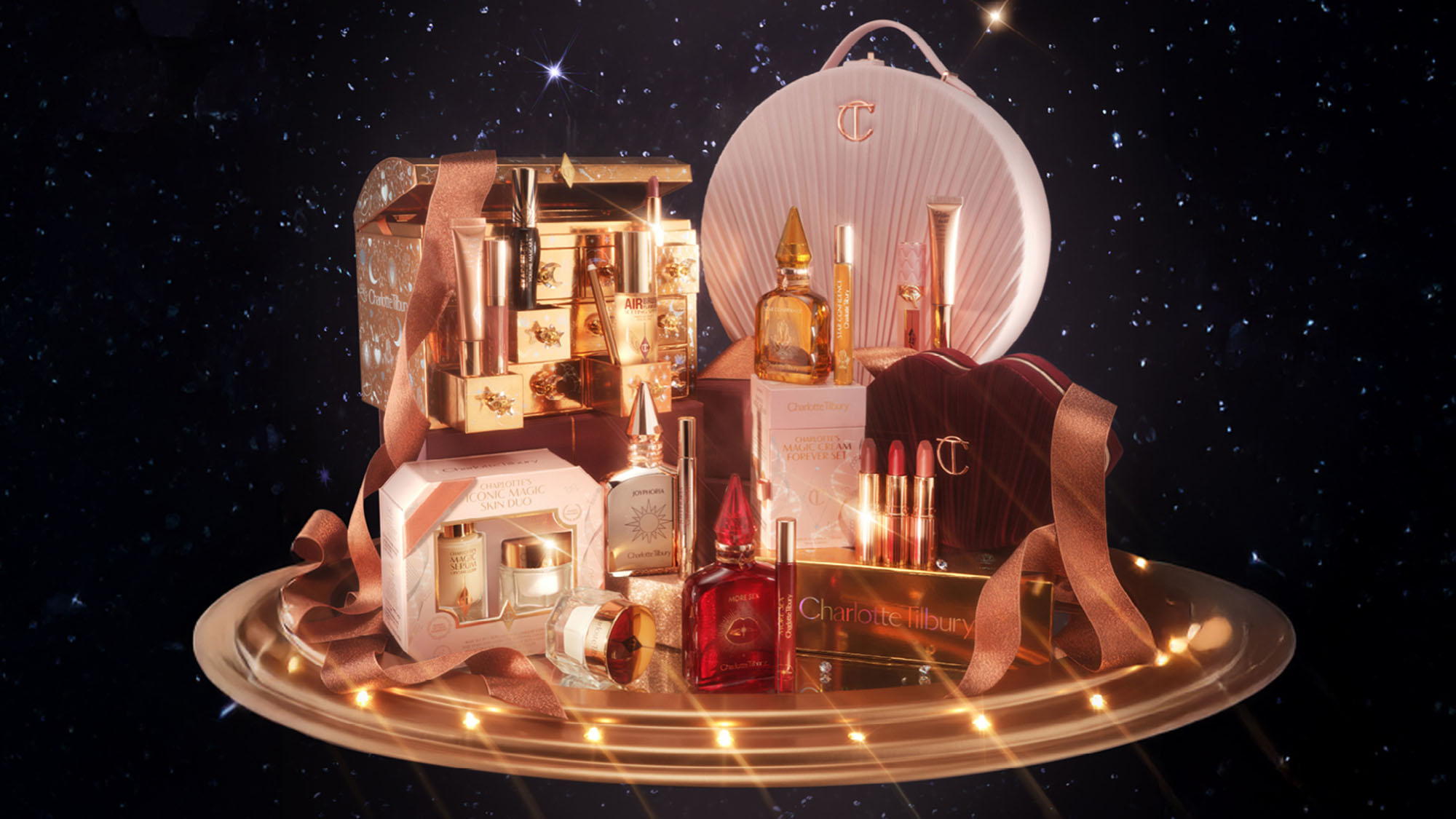 A luxurious display of beauty products with gold accents, set against a starry night background, featuring perfumes, lipsticks, and ornate packaging.