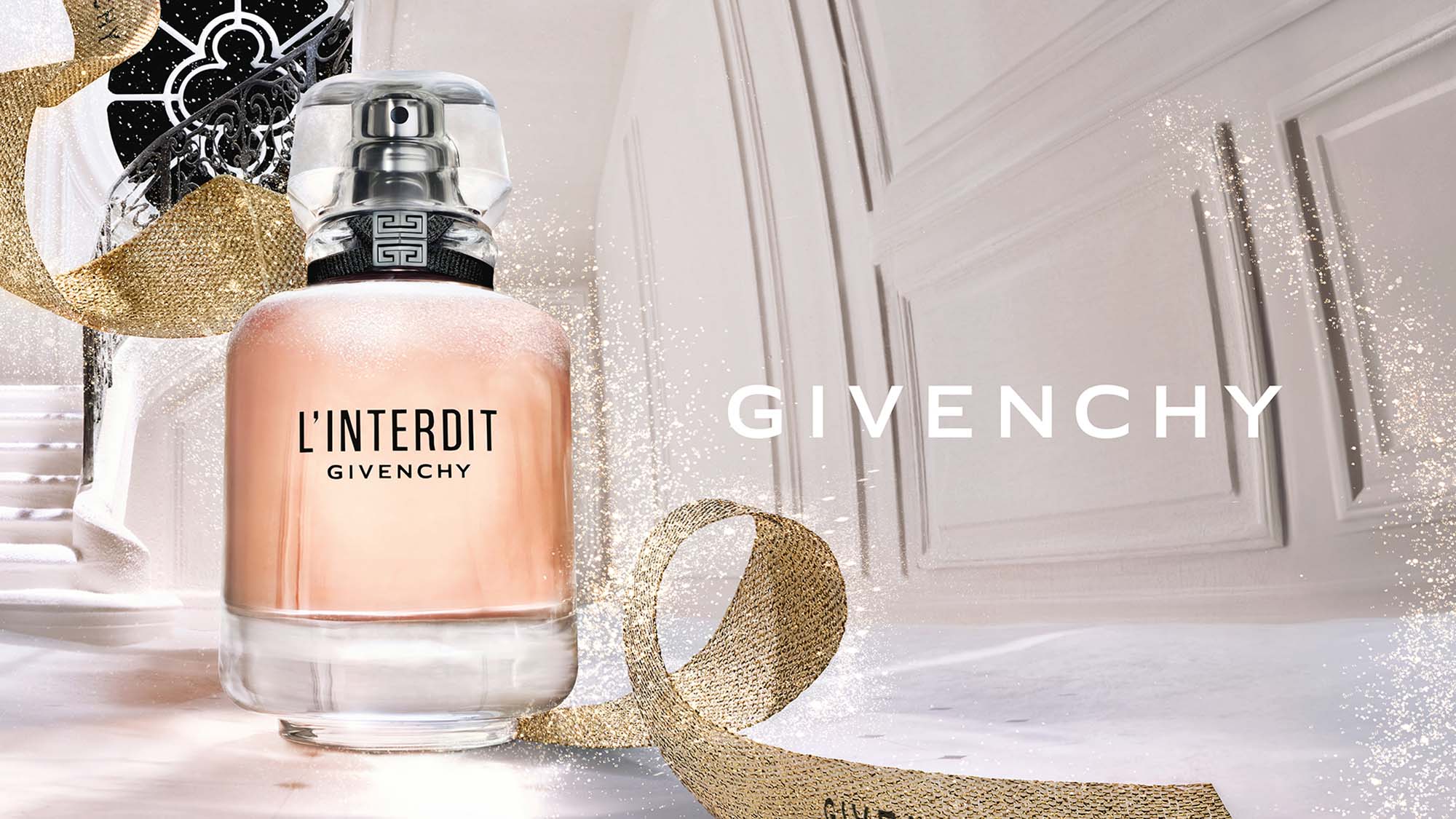 Perfume bottle of L'Interdit by Givenchy against an elegant white background with a sparkling ribbon.