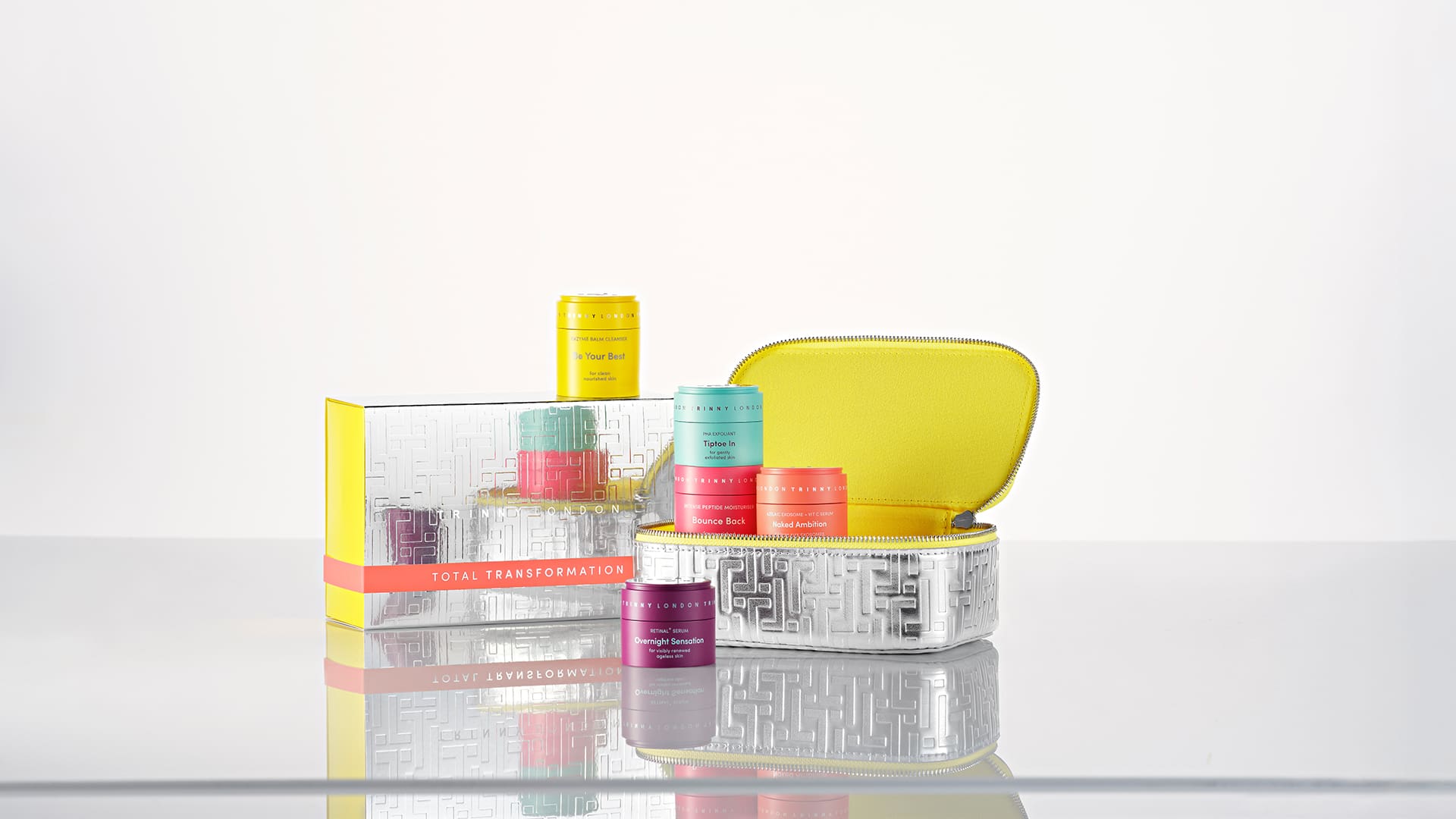 A colorful skincare set with various jars and a carry case on a reflective surface.