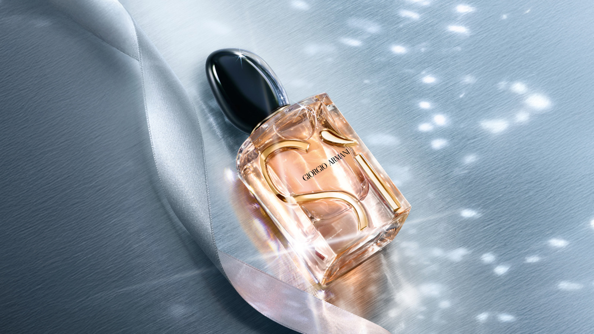 A Giorgio Armani perfume bottle with a black cap and golden accents, set against a shimmering background with soft lighting.