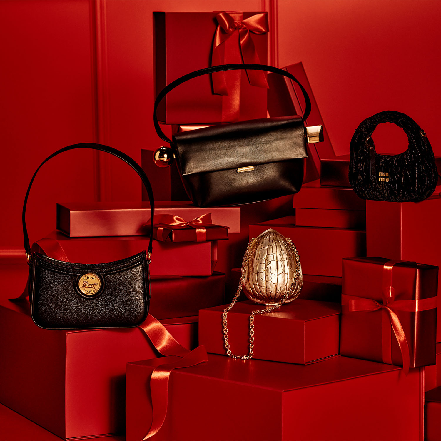 Various handbags and a gold purse displayed on red gift boxes.