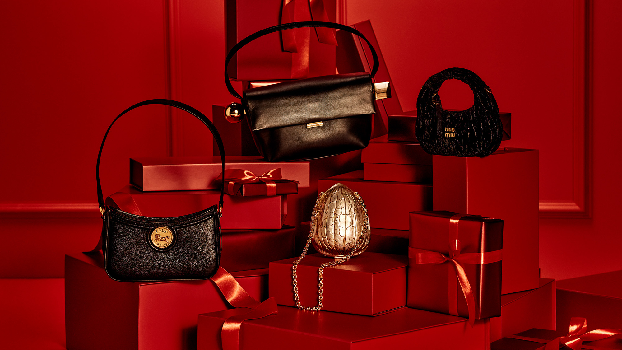 Various handbags and a gold purse displayed on red gift boxes.