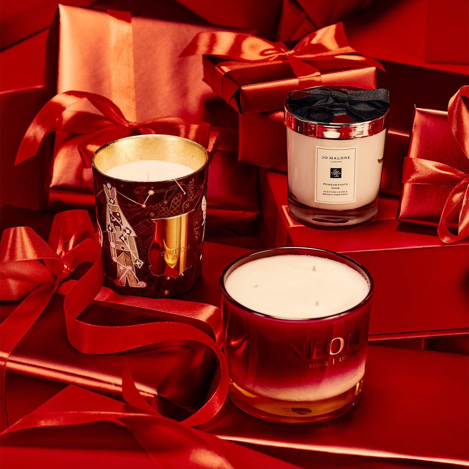 Three candles on red gift boxes with ribbons.