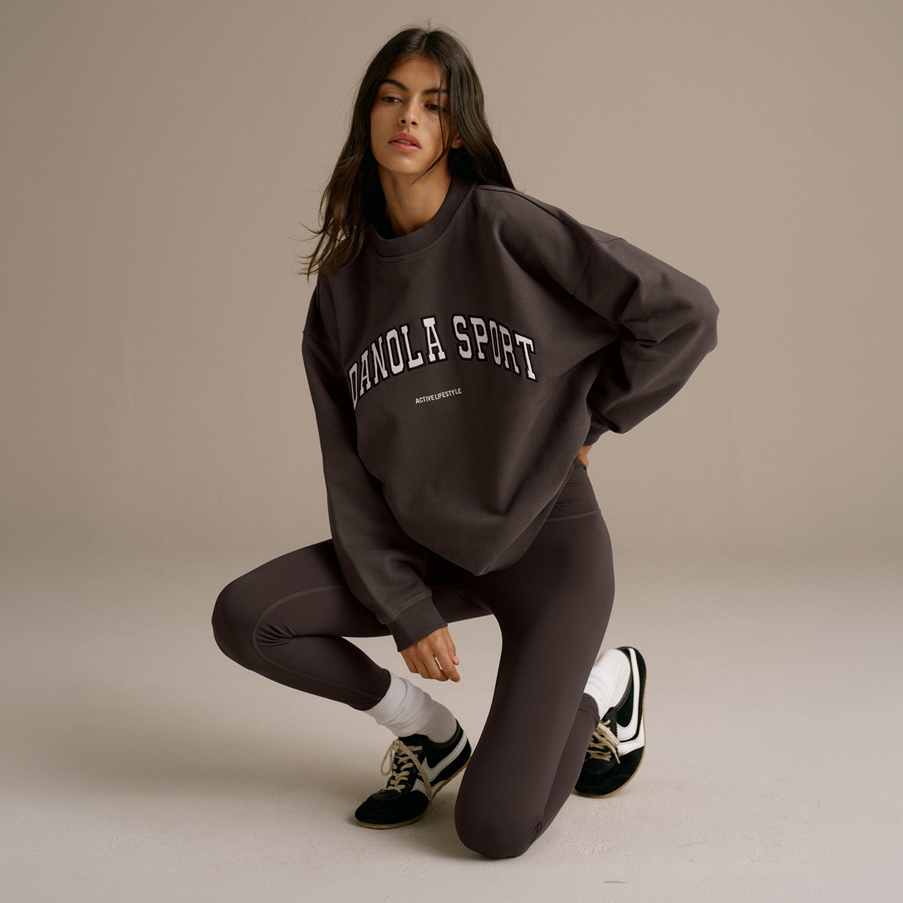 Woman wearing black Adanola Sport sweatshirt and black leggings with black and white trainers