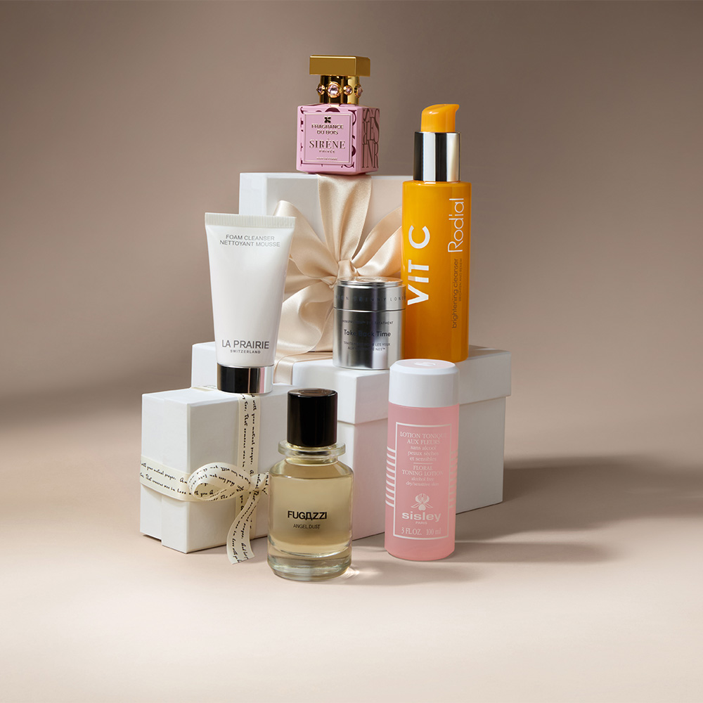 A collection of skincare products and perfumes arranged on white gift boxes with ribbons.