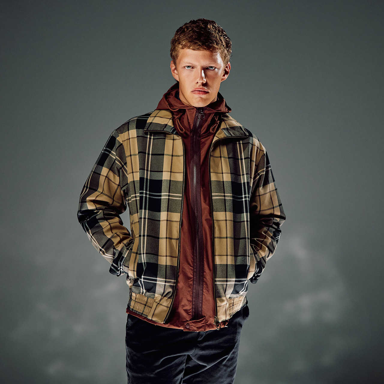 Man wearing tan and black check Barbour jacket over burgundy hooded jacket, styled for layering