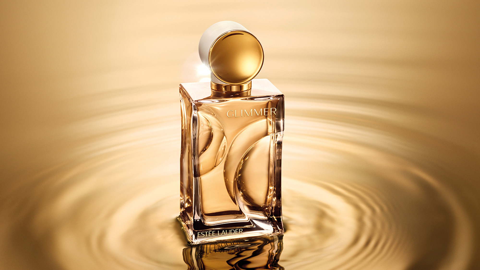 Glimmer Eau de Parfum bottle with gold liquid and white cap on warm golden background