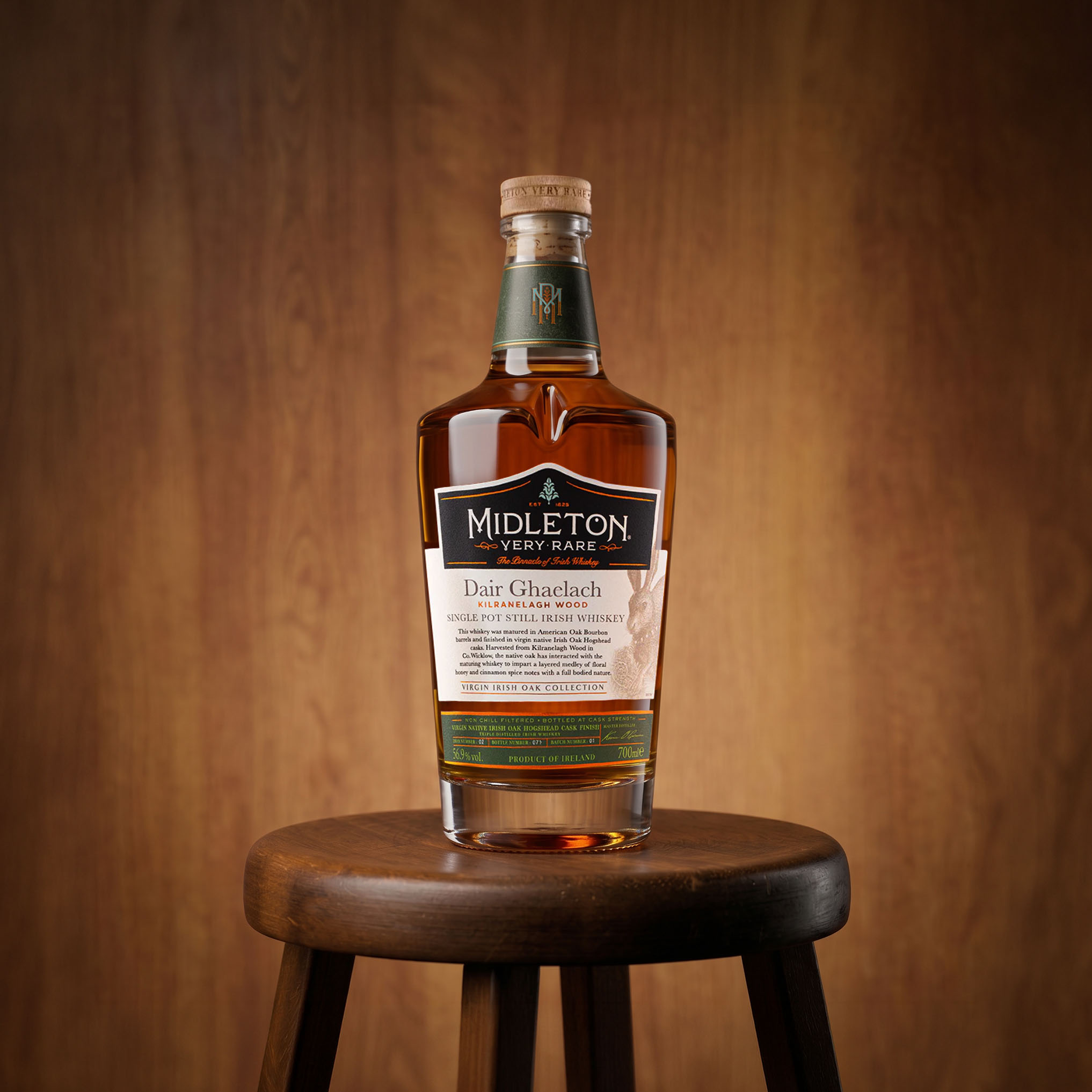 Midleton Very Rare Dair Ghaelach Irish whiskey bottle displayed on wooden stool against wood panelled background