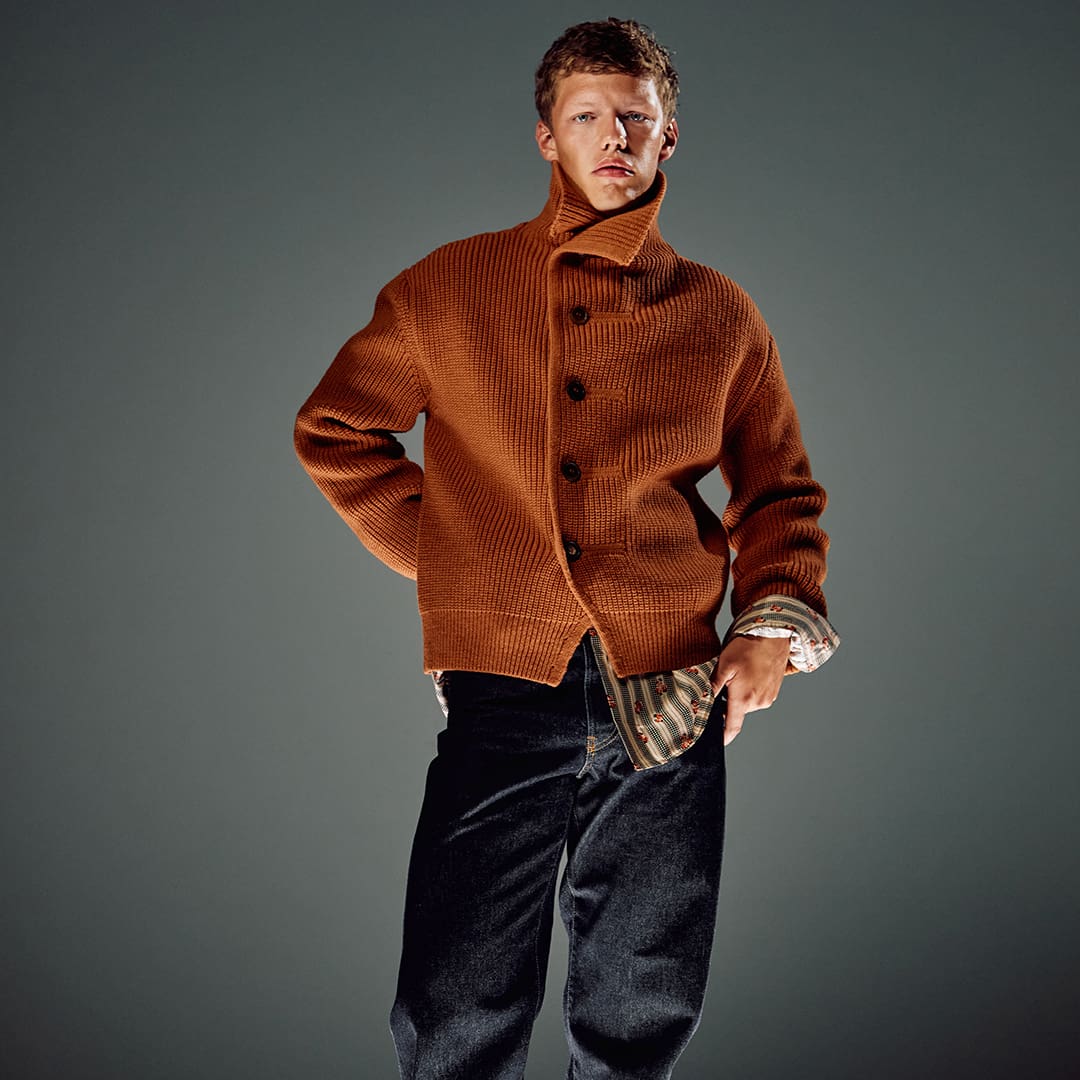 Man wearing rust-coloured ribbed shirt with collar against grey background