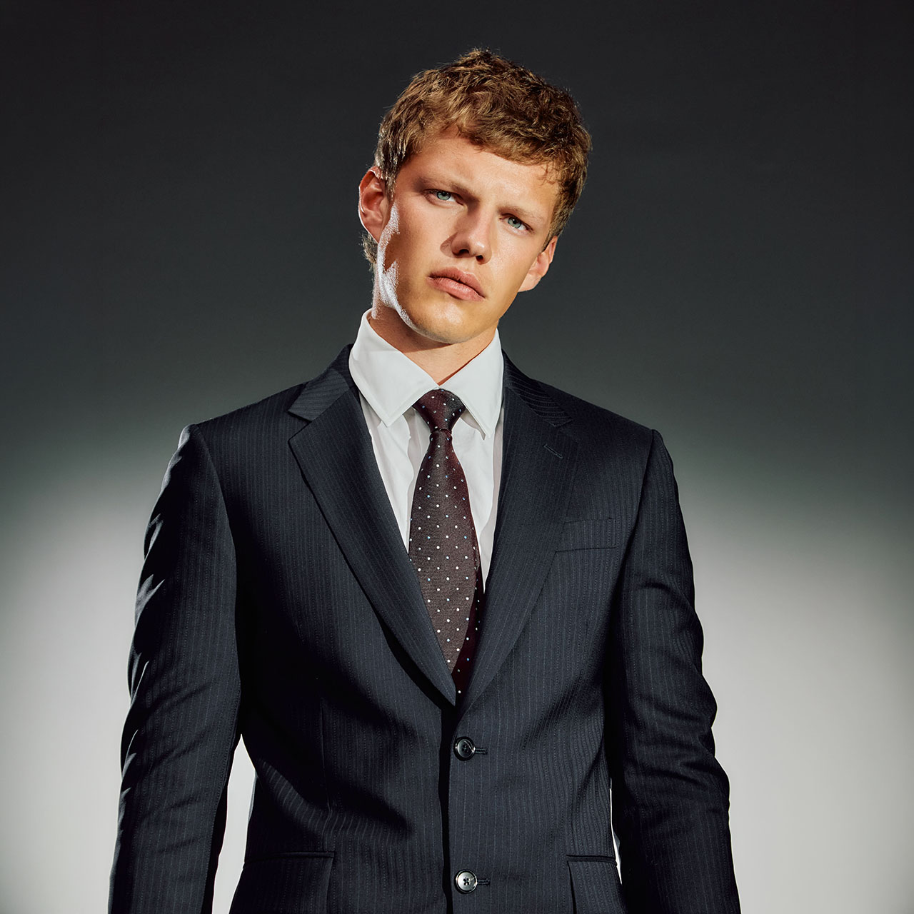 Man wearing navy pinstriped suit with white dress shirt and burgundy dotted tie