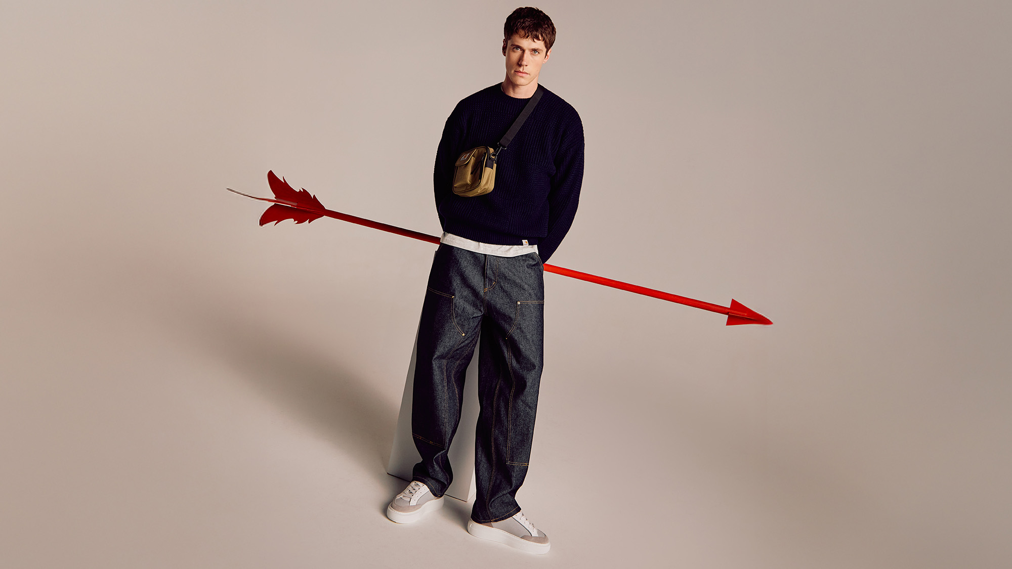 A person in casual clothing stands with a large red arrow photoshopped to appear piercing their torso.