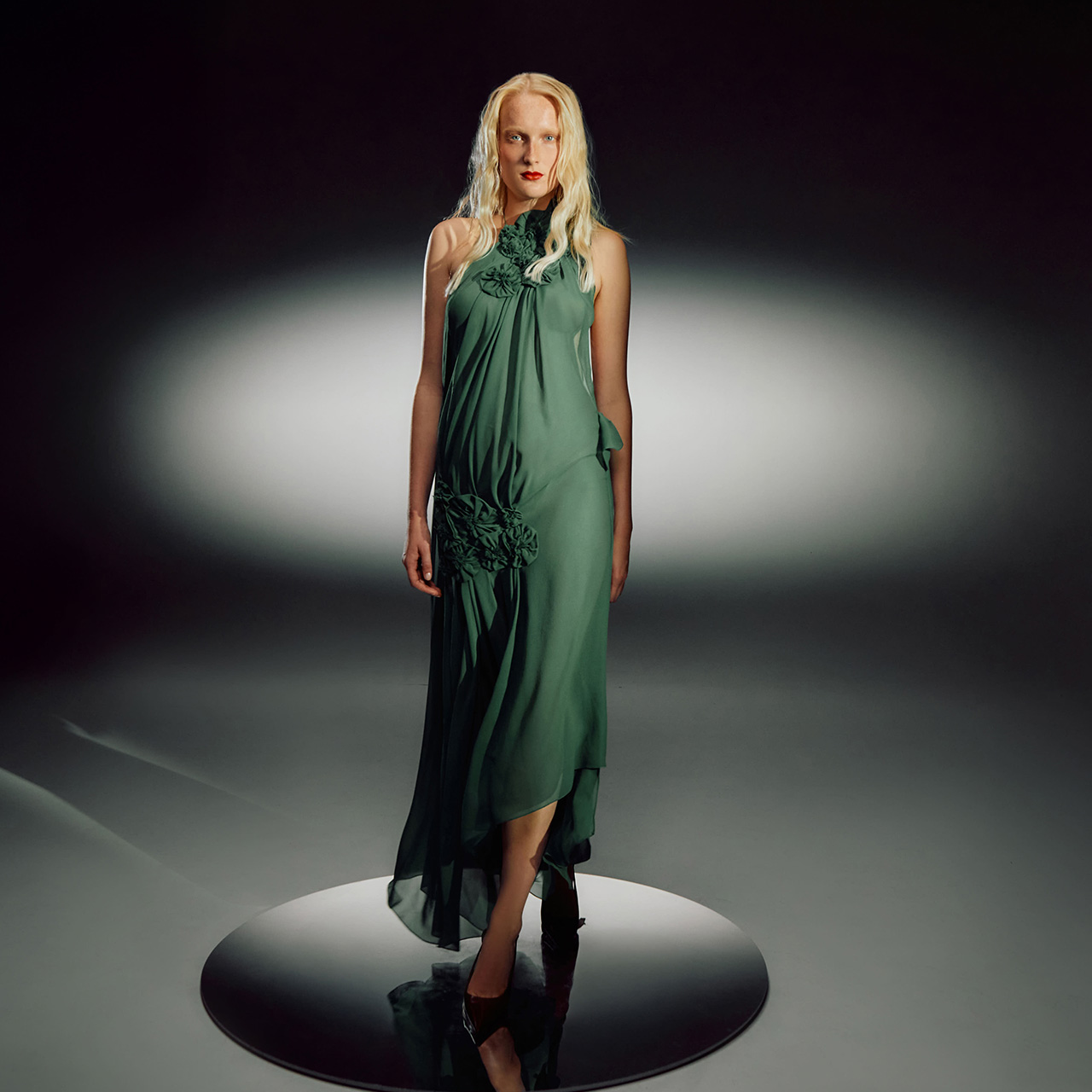 Woman wearing flowing sage green sleeveless dress with decorative ruching detail