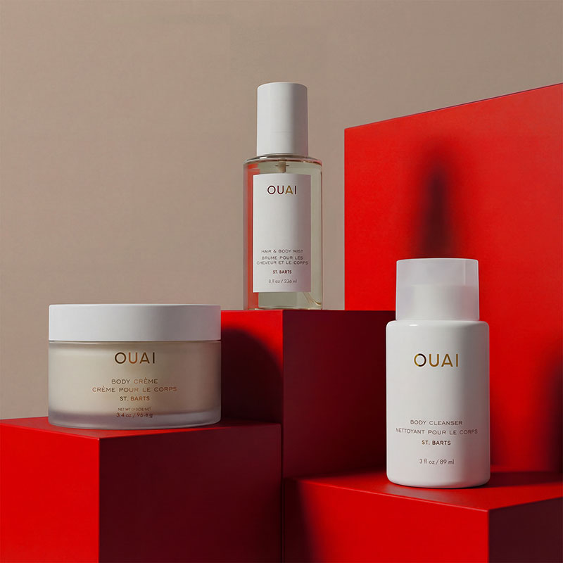 Three Ouai skincare products displayed on red geometric blocks against a neutral background.