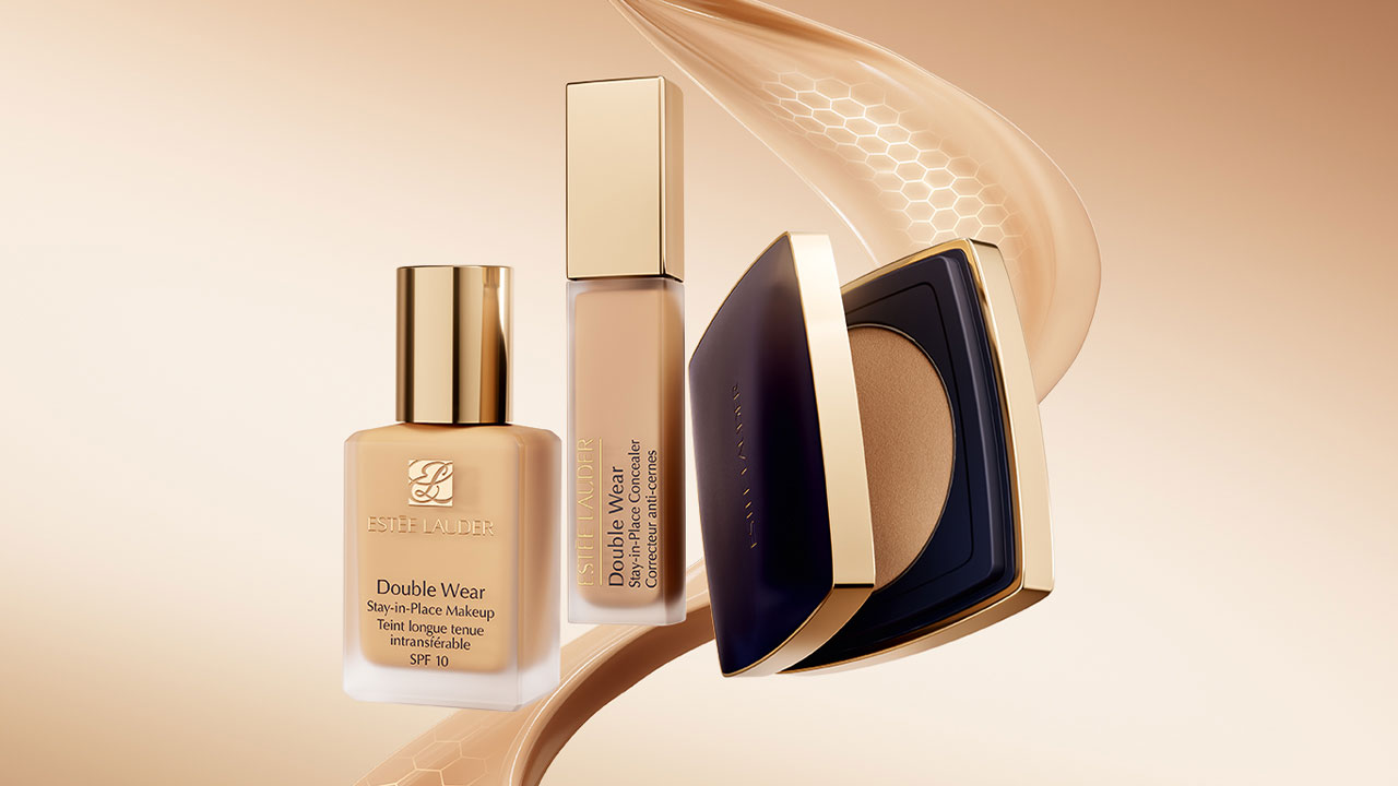 Three cosmetic products, including liquid foundation, concealer, and compact powder, are arranged on a beige background.
