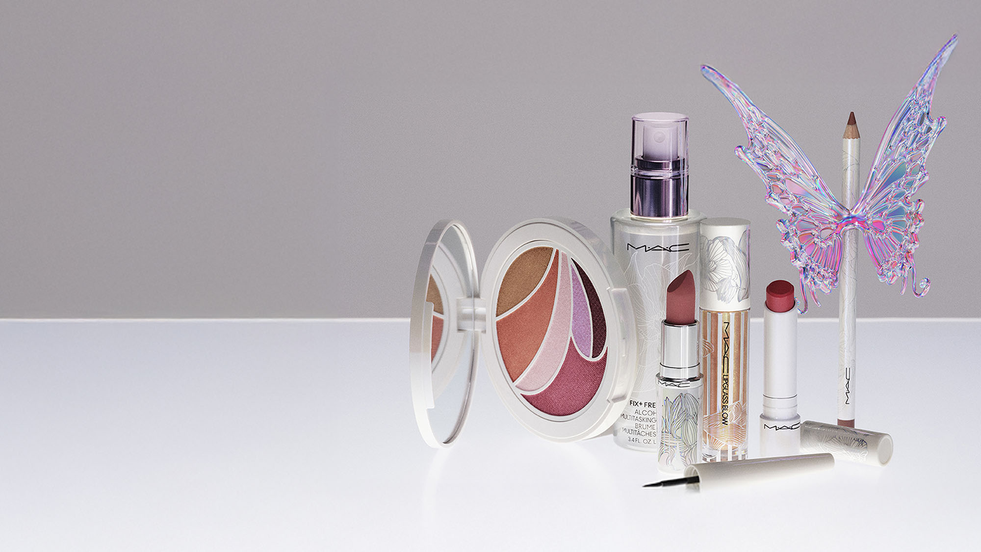 A collection of makeup items including lipsticks, a compact, eyeliner, and an iridescent butterfly ornament.