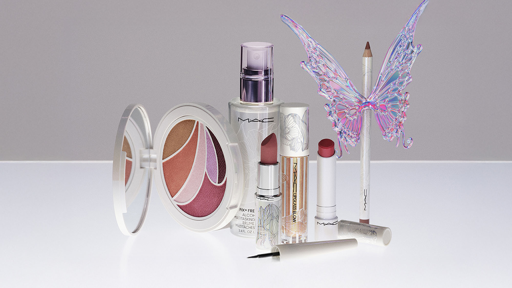 A collection of makeup items including lipsticks, a compact, eyeliner, and an iridescent butterfly ornament.