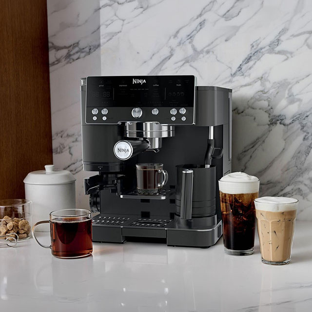 Espresso machine on a counter with various coffee drinks and containers nearby.