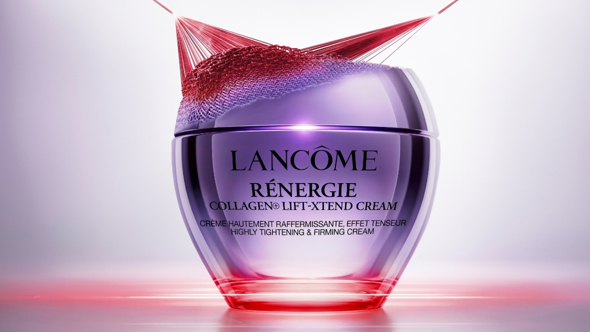 A Lancôme Renergie Collagen Lift-XTend Cream jar with a purple hue and red accents, highlighted by dramatic lighting.