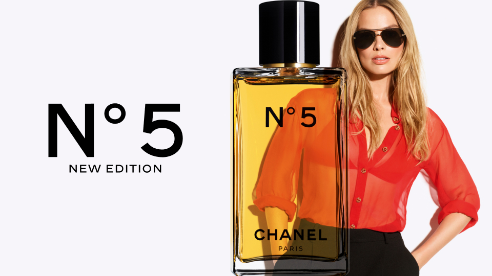 Chanel No. 5 New Edition perfume bottle alongside a woman in a red blouse wearing sunglasses, with text detailing the fragrance on a light background.