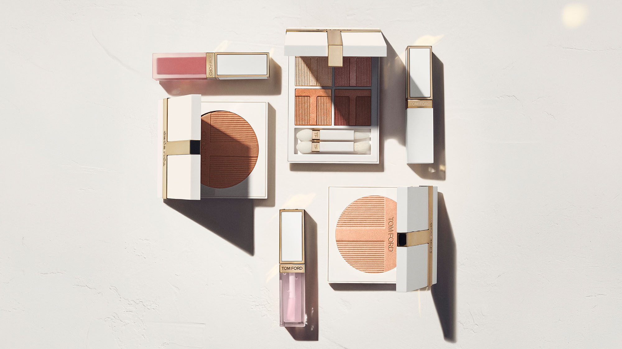 Tom Ford Soleil Summer Collection makeup and skincare products arranged on a light background, featuring sunset-toned eyeshadow palettes, lipstick, and bronzer with gold accents