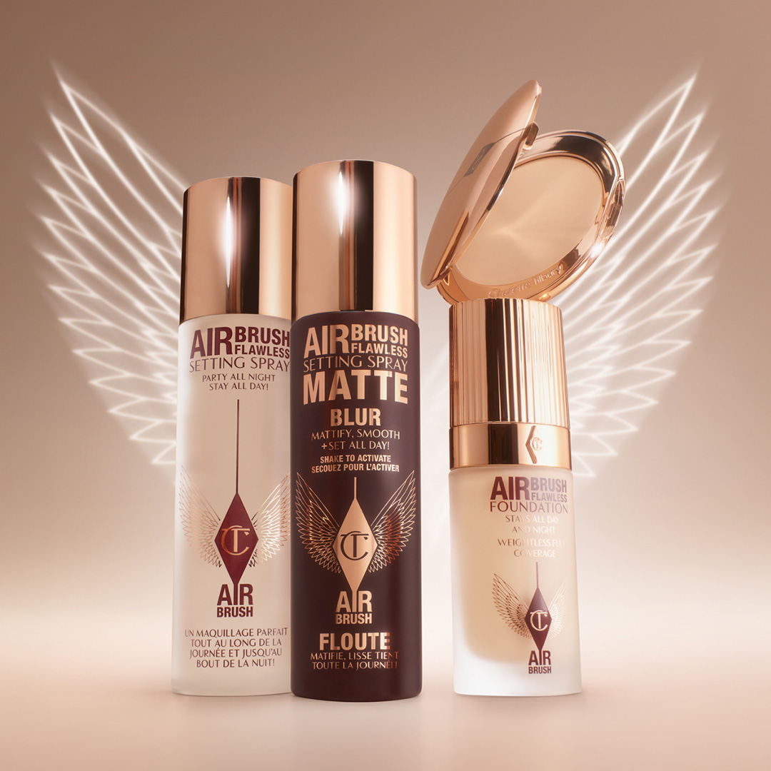 Charlotte Tilbury Airbrush foundation and setting spray bottles with matching concealer, surrounded by decorative pearl spheres