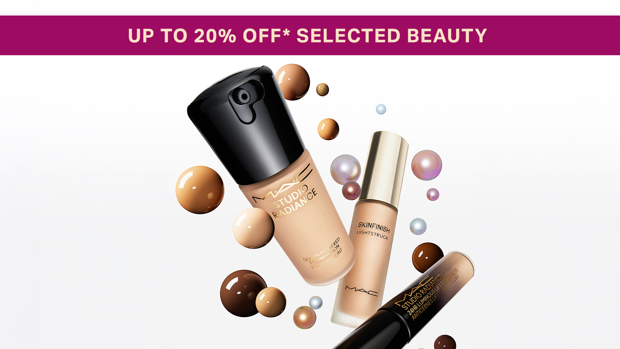 Collection of makeup products including foundation, highlighter and mascara with decorative coloured spheres