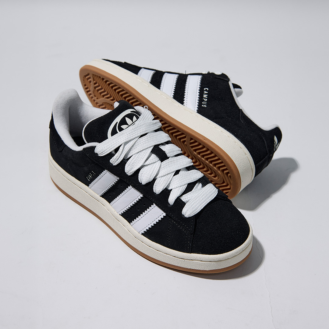 Black and white trainers with cream sole and gum base, white laces, displayed with matching striped socks