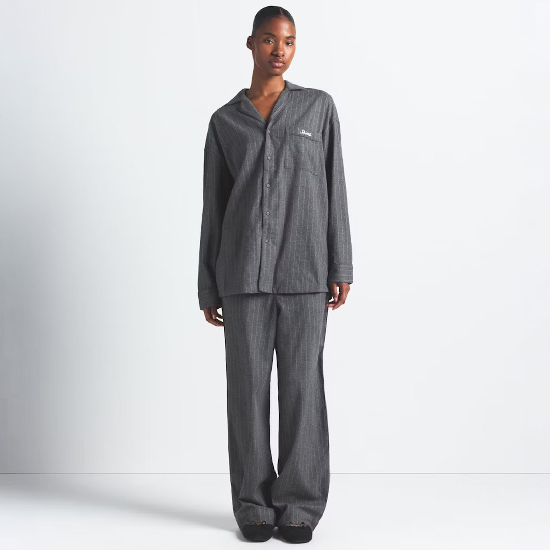 Woman wearing charcoal grey button-up shirt and wide-leg trousers with minimal branding