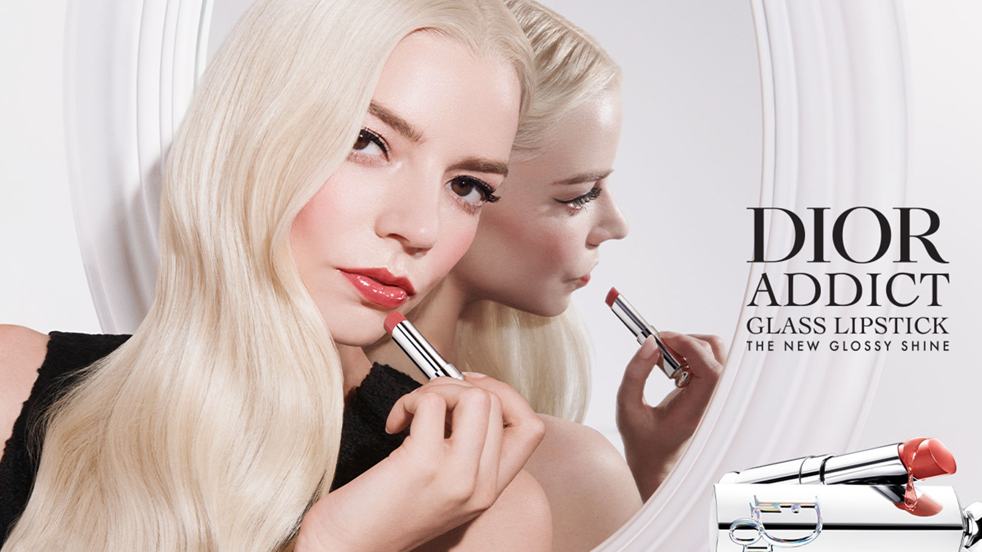 A person with long blonde hair applies lip gloss, reflected in a mirror. The image promotes Dior Addict Glass Lipstick.