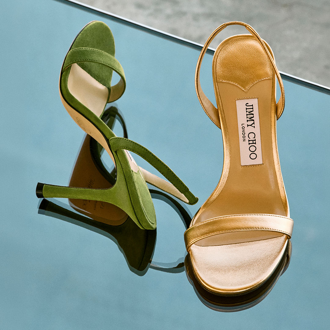 Green suede and gold metallic sandal and gold leather slingback sandal displayed against blue background