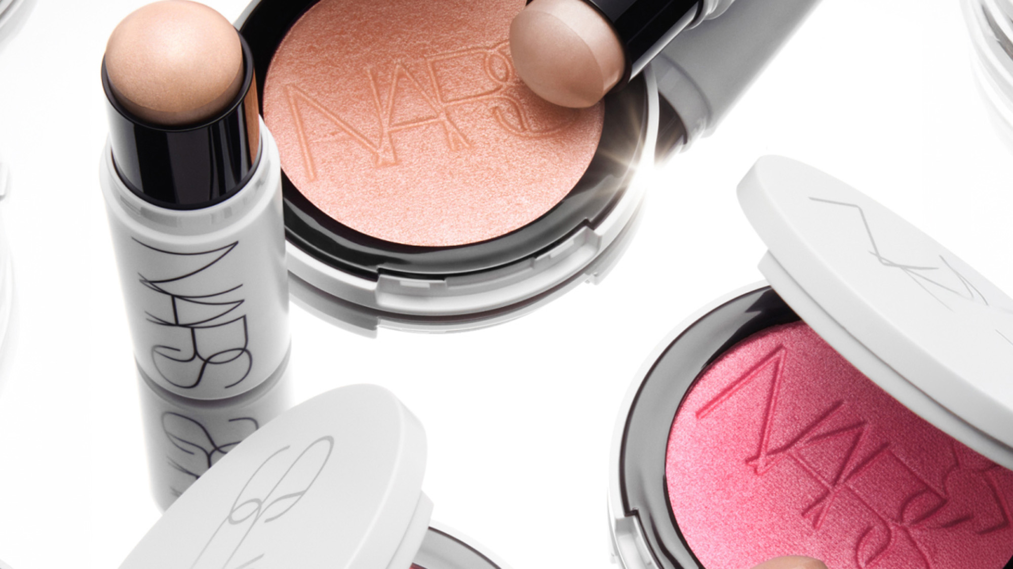 NARS cosmetics collection featuring white spray bottle, peach eyeshadow palette, and pink blush compact with brand logo