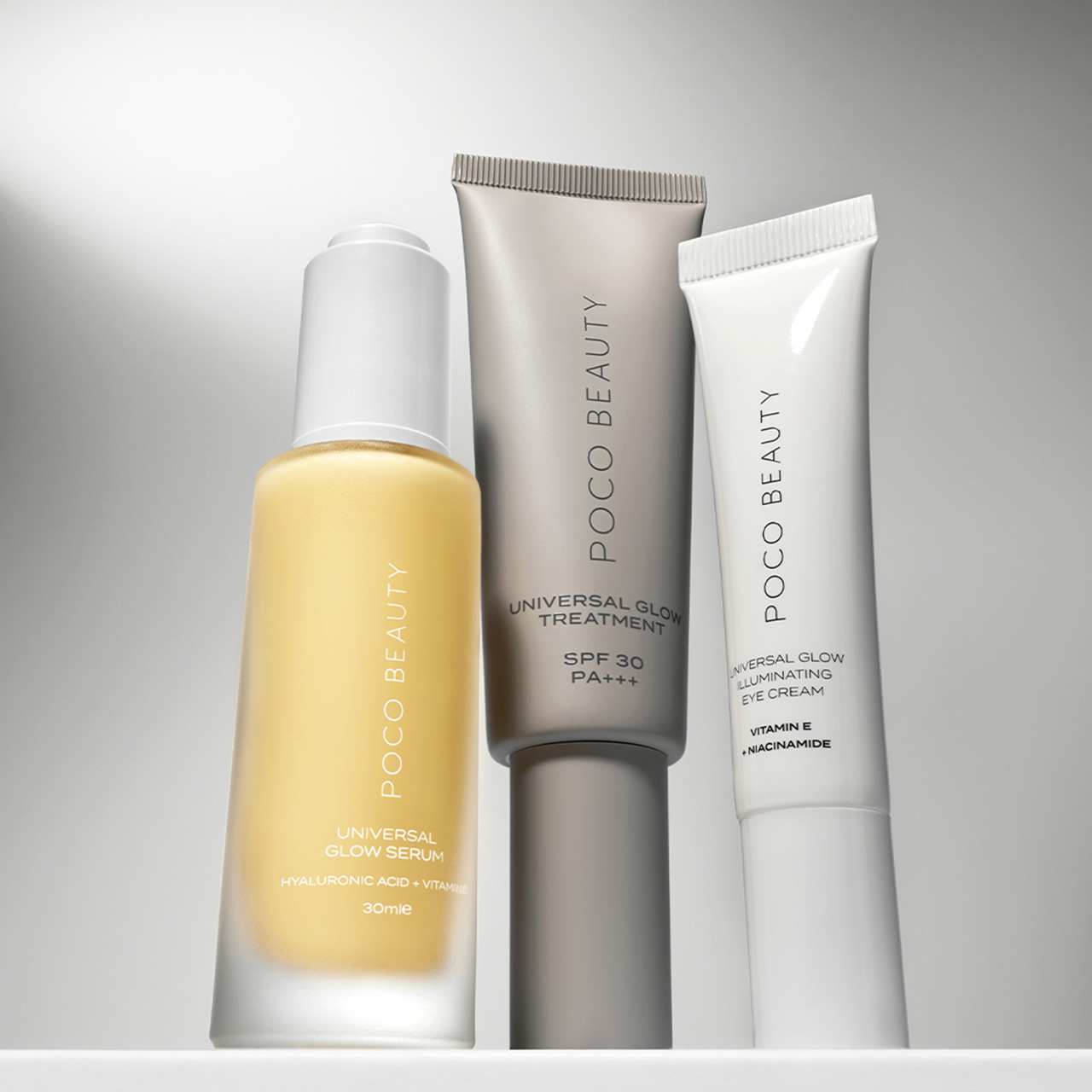 Three Poco Beauty skincare products on a reflective surface with soft lighting.